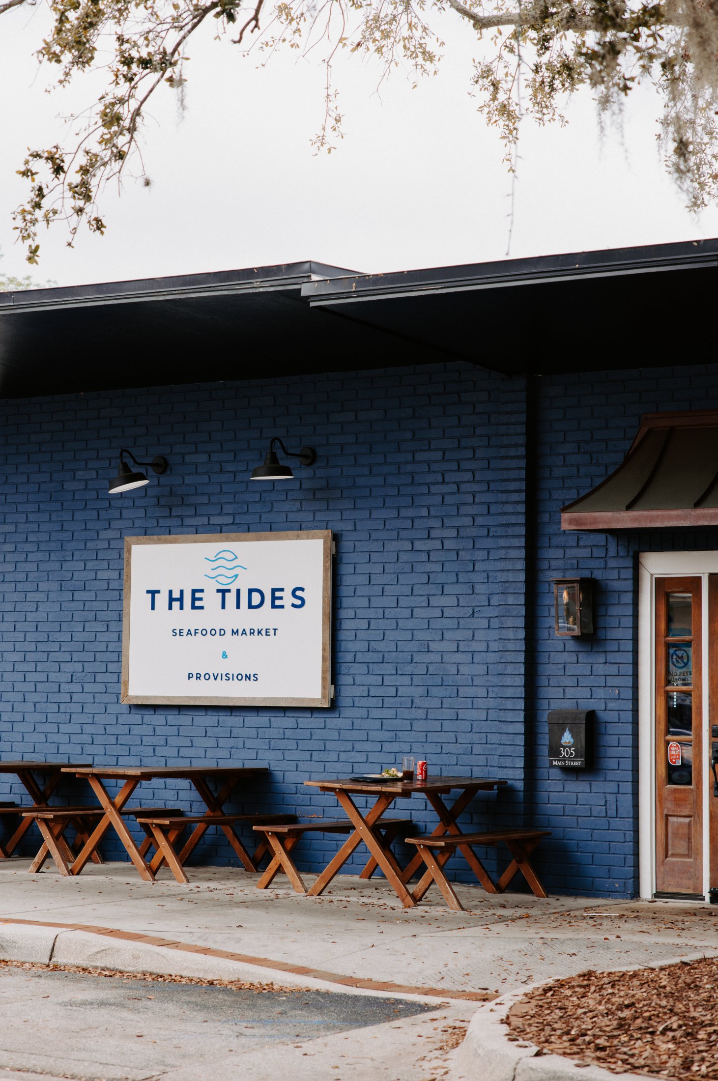 Picnic tables beneath The Tides Seafood Market & Provisions sign on Main Street, Safety Harbor FL
