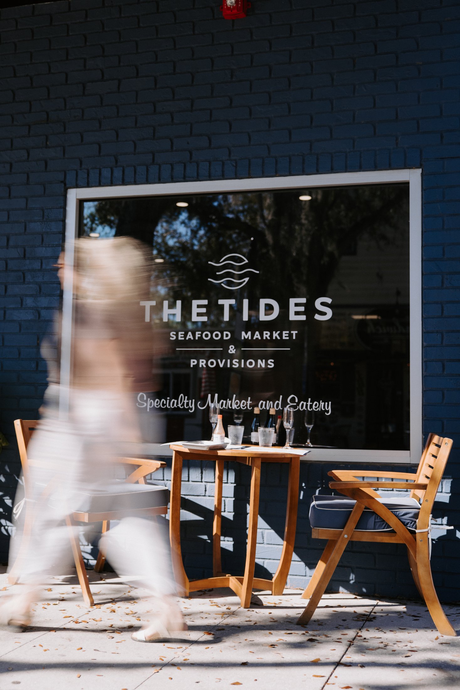 A passerby in motion in front of The Tides Seafood Market window in Safety Harbor FL