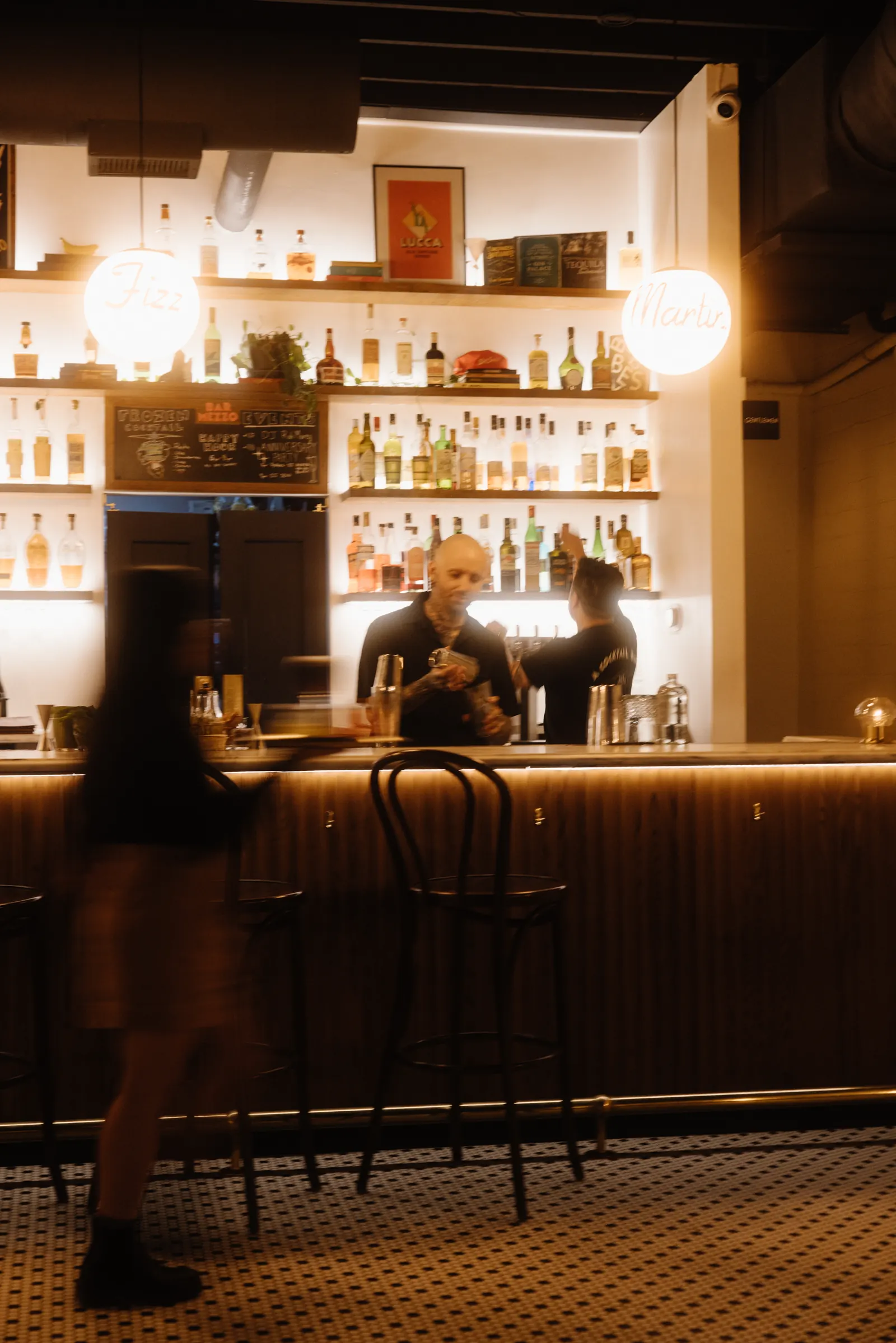 Guest walking past the back bar at Bar Mezzo with motion blur, ambient light bar photography
