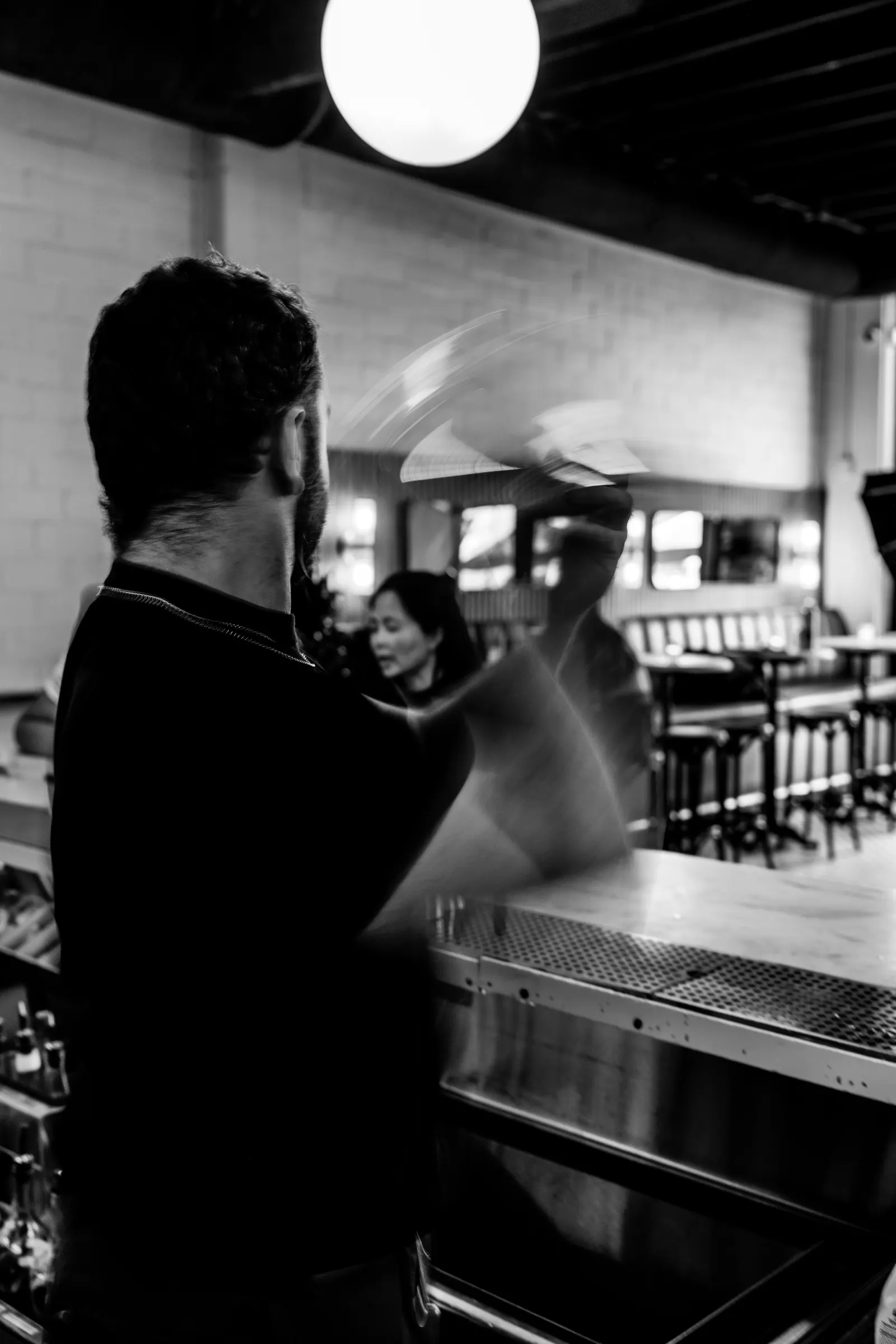 Black and white photo of a bartender shaking a cocktail with motion blur at Bar Mezzo