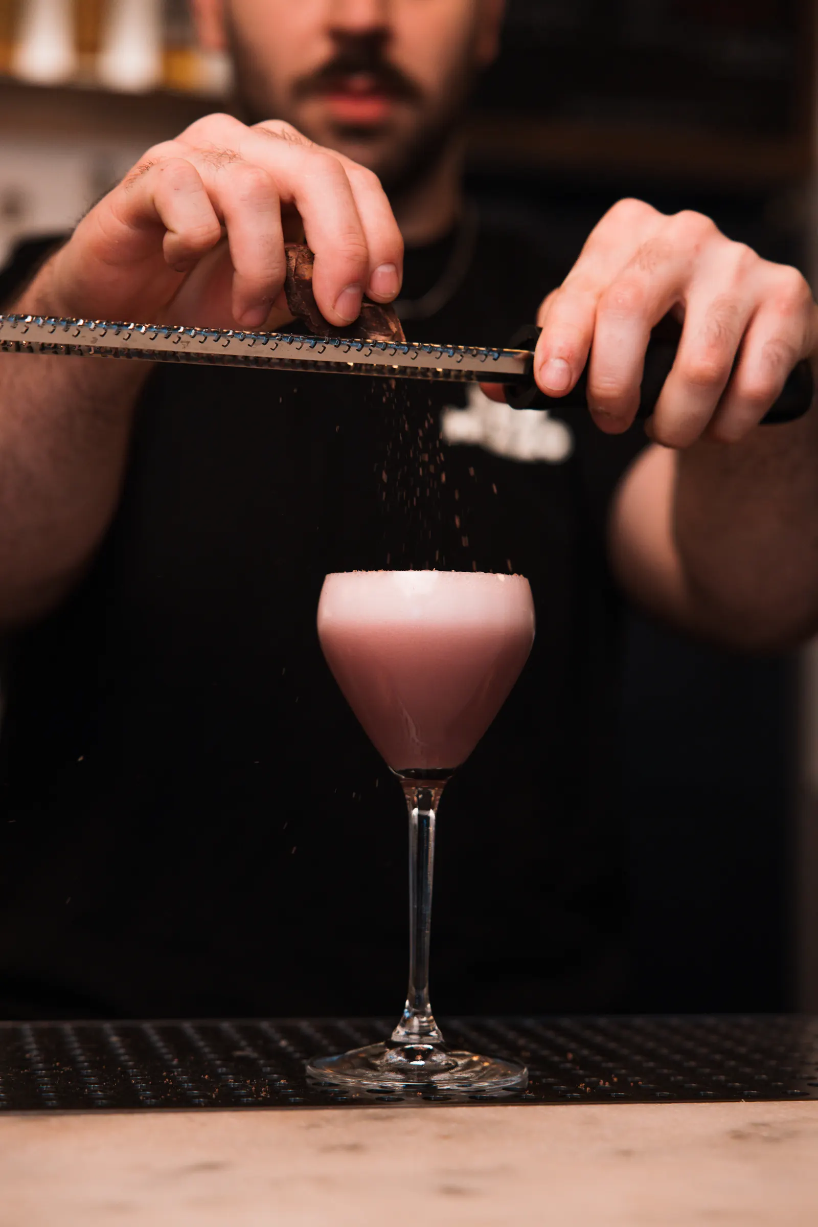 Bartender grating garnish over a pink cocktail at Bar Mezzo, cocktail bar photography St. Petersburg