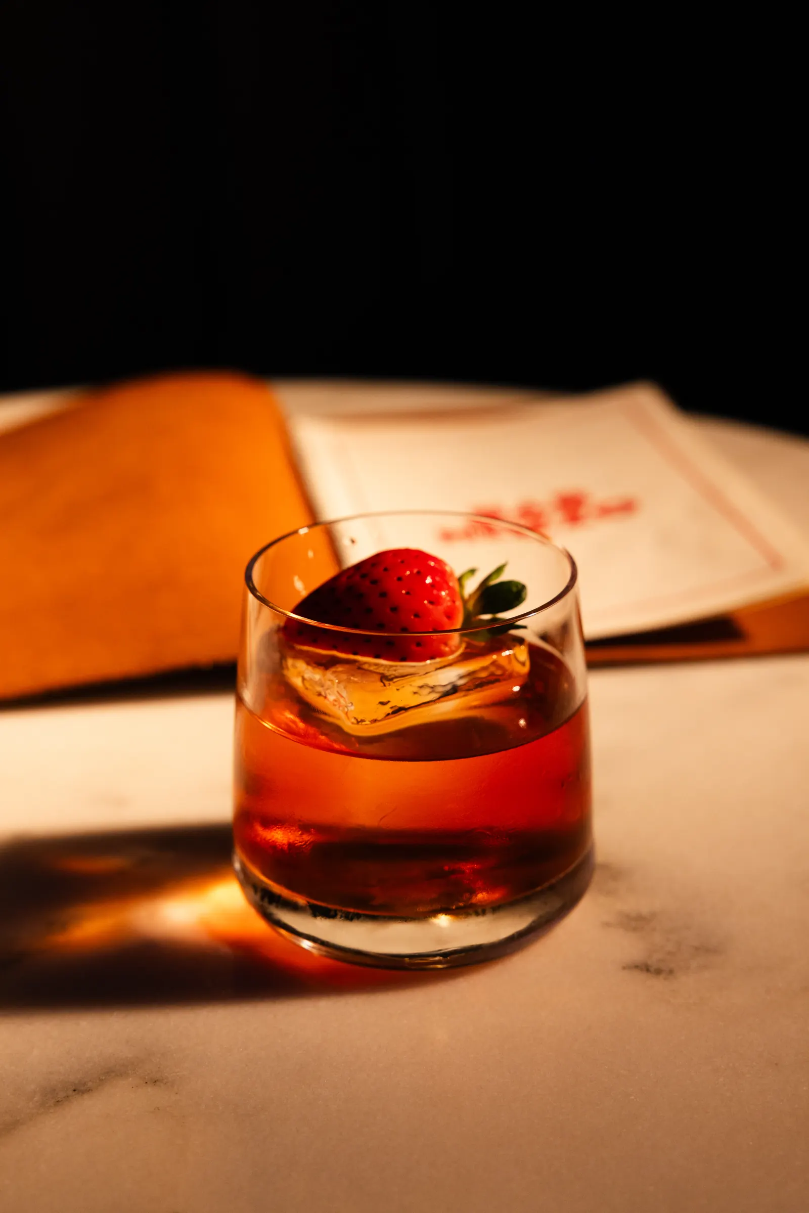 Old fashioned with a strawberry garnish and the Bar Mezzo menu, cocktail photography