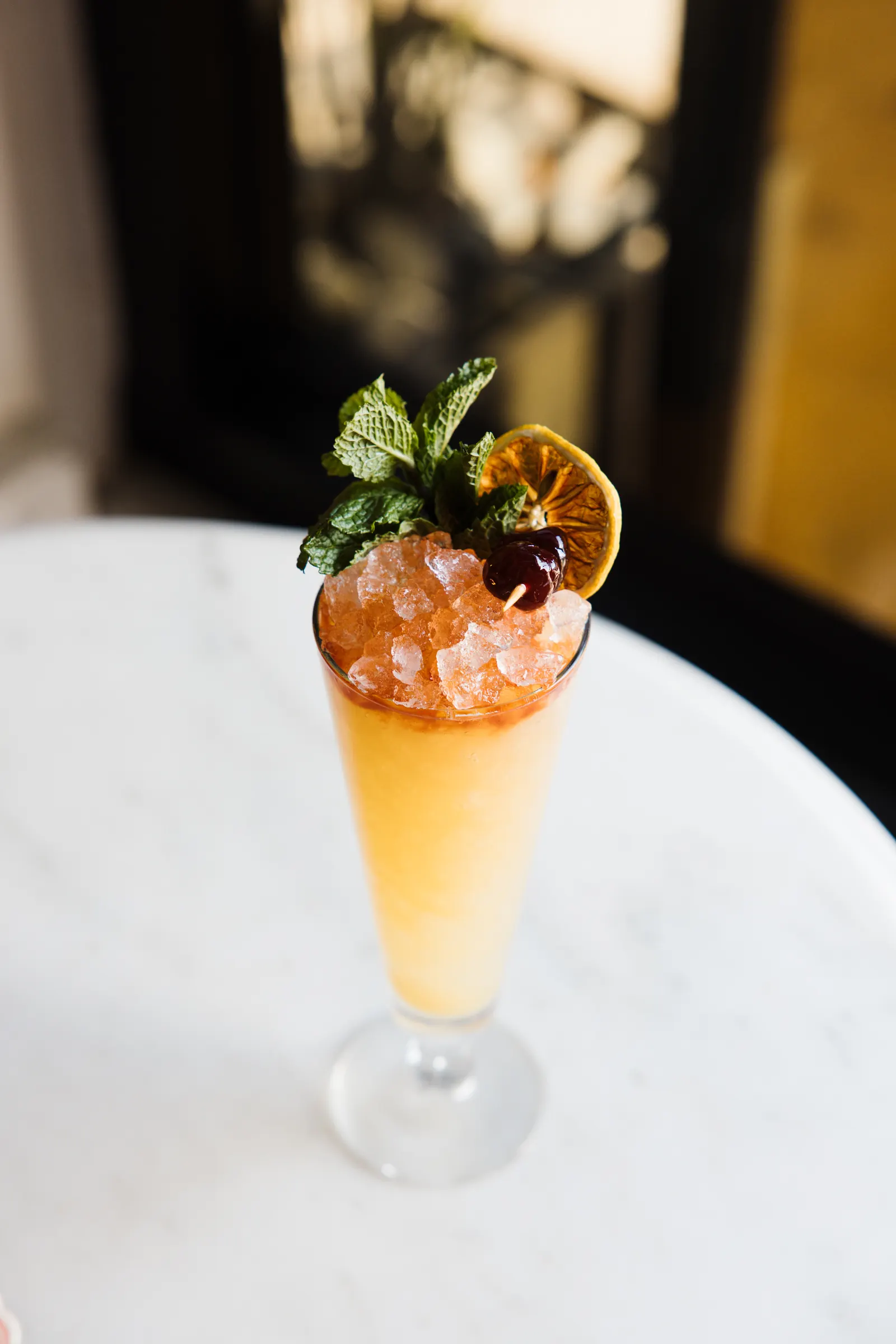 Tropical cocktail with mint and citrus garnish on a marble table at Bar Mezzo, cocktail photography by Orange Grove Social