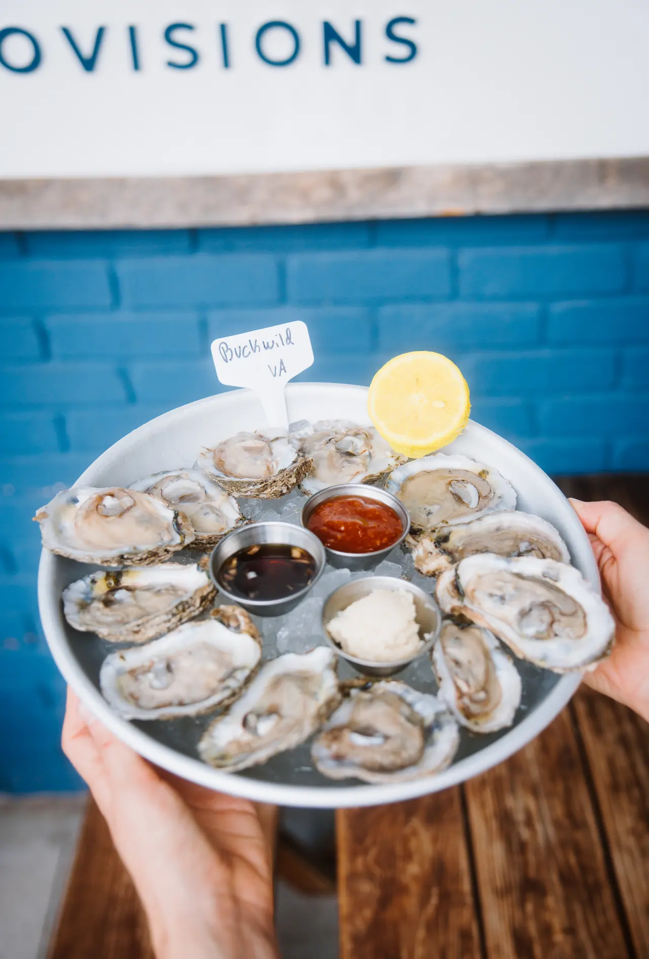 Platter of raw oysters on the half shell held up at The Tides Market, photographed by Orange Grove Social