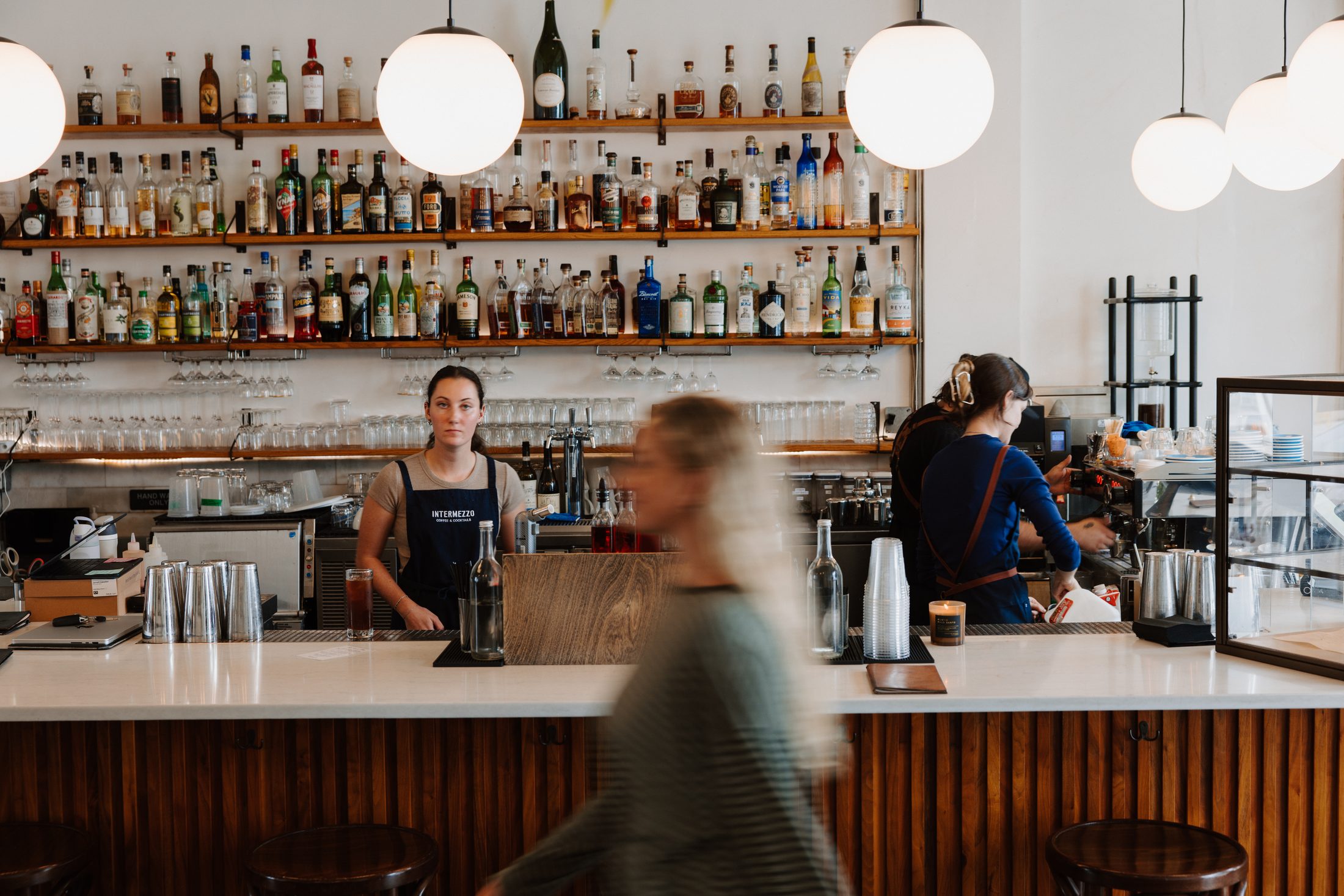 The coffee and cocktail bar at Intermezzo, St. Petersburg FL, with a guest walking past — photography by Orange Grove Social