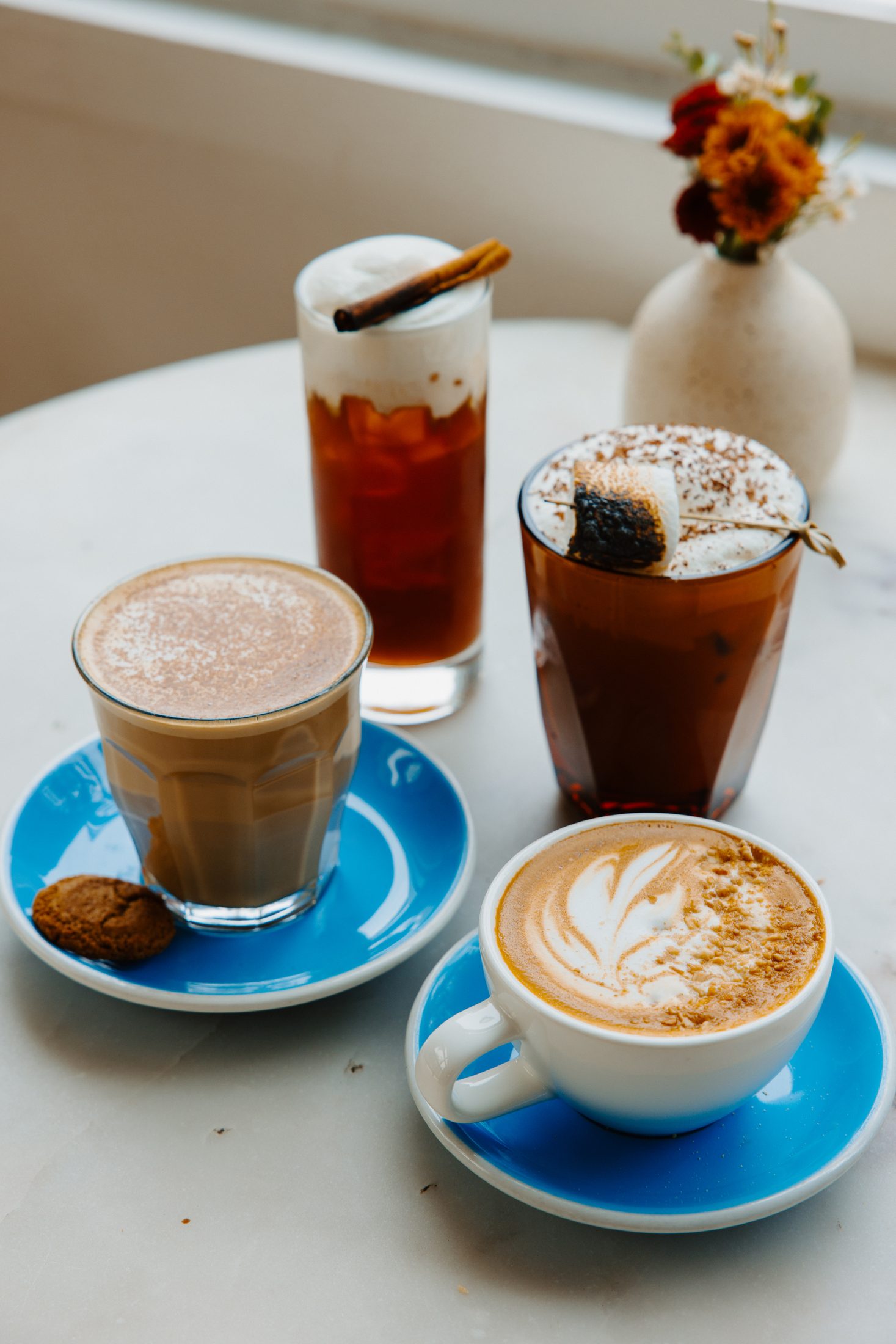 Four fall coffee drinks on a marble café table at Intermezzo, St. Petersburg FL — hospitality photography by Orange Grove Social